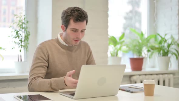 Man Talking on Video Call on Laptop in Office alt