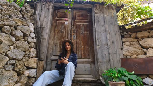 Woman Looking at Camera Sitting in Front of Door alt