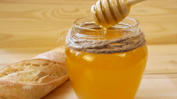 Golden Liquid Honey Flows From a Spoon Into a Jar