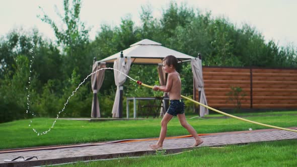 The Two Boys Are Playing with Mom and Dad in the Backyard of Their House Drenching with Hose alt