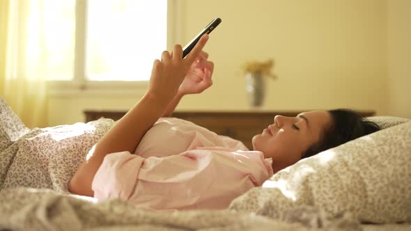 The Girl Turns Off the Alarm Clock in the Morning in Bed and Gets Up alt