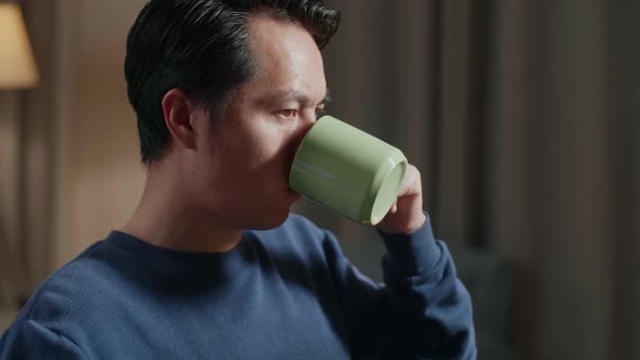 Side View Of Asian Male Engineer With The House Model Drinking Coffee While Working On A Desktop alt