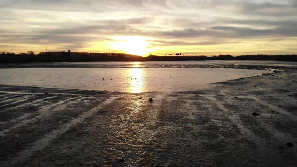 Sunset on a low water tidal lake where ducks are swimming around on a calm partly cloudy summer day alt