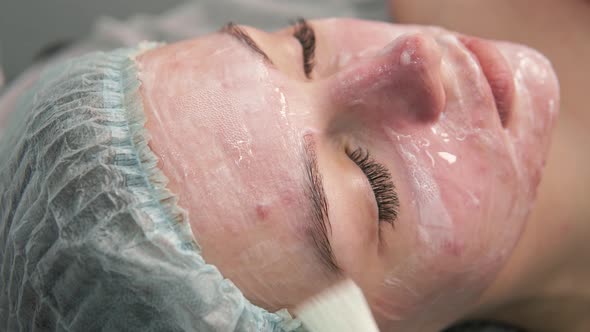 The Cosmetologist Applies a Gel Brush to the Face of a Young Female Client