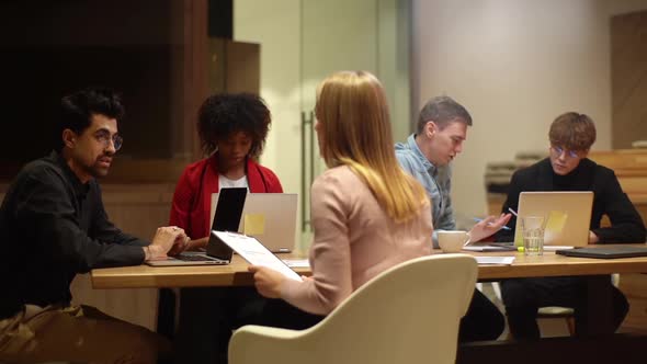 Remote View of Young Startup Team of Diverse Young Business People Working Sitting at Table with alt