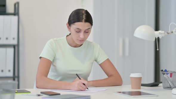 Young Latin Woman Writing on Paper at Work alt