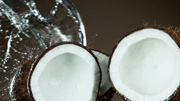 Super Slow Motion Shot of Flying Fresh Coconuts and Water Side Splash on Brown at 1000Fps alt