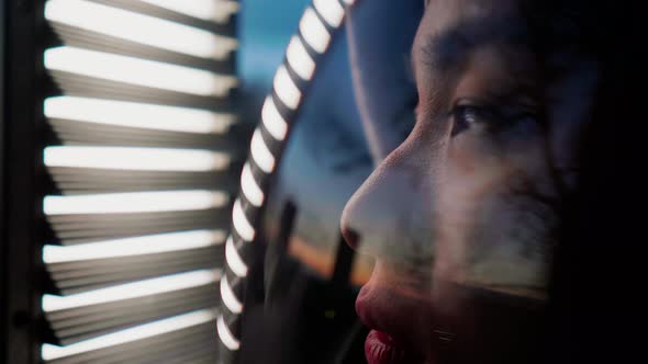 Woman in space helmet looking through window blinds