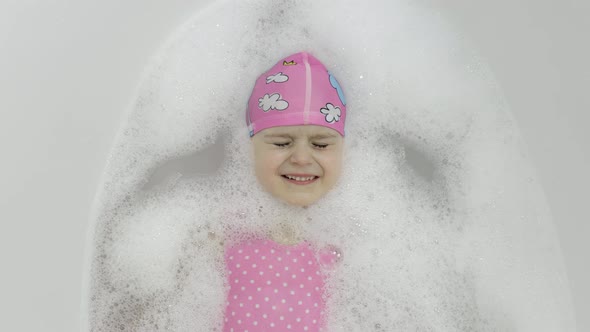 Cute Blonde Girl Takes a Bath in Swimwear. Little Child Washes Her Head alt