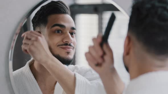 Arabian Spaniard Arab Man Looking at Mirror Combing Hair with Hairbrush Getting Ready in Bathroom alt