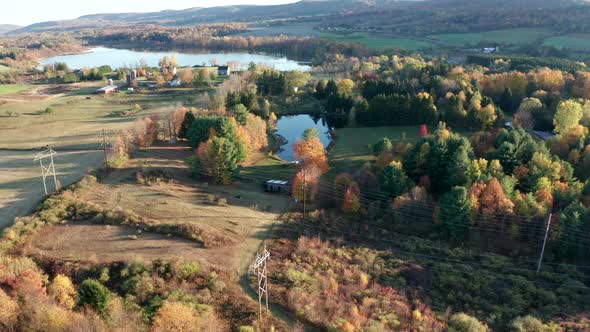 Aerial Drone Shot Flying Towards Power Lines and Farm with Pond and Fall Colors alt