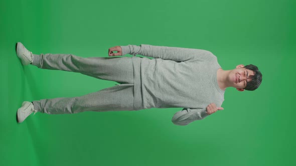 Full Body Of Asian Man Showing Thumbs Up Gesture And Smiling On Green Screen Studio alt