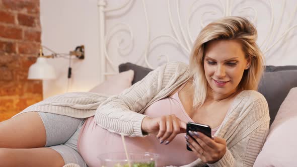 Pregnant Woman on the Bed Scrolling Social Media alt