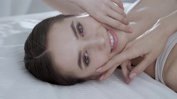 Face Care. Young Woman Lying On Bed And Touching Skin On Face alt