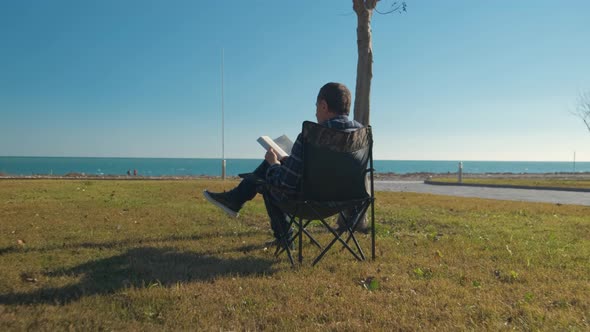 Man Reading Book Sitting on Chair