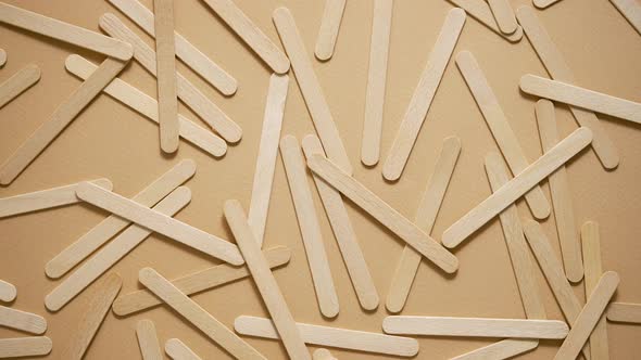 Wooden Popsicle Sticks Scattered on Top of a Beige Background