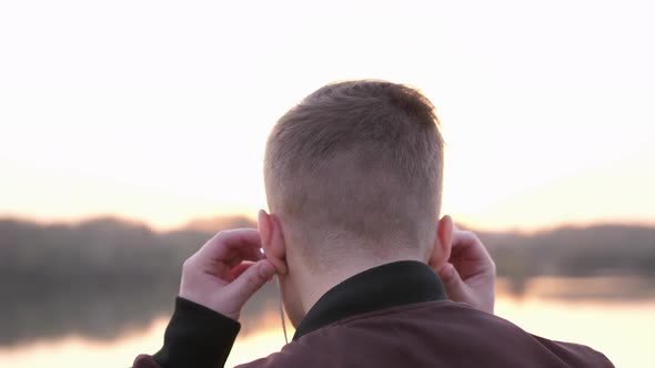 Back View of Man Listens to Music on Beach Looks Amazing Sunset