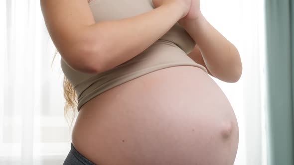 Yougn Pregnant Woman with Big Belly Meditating and Practicing Yoga at Big Window alt