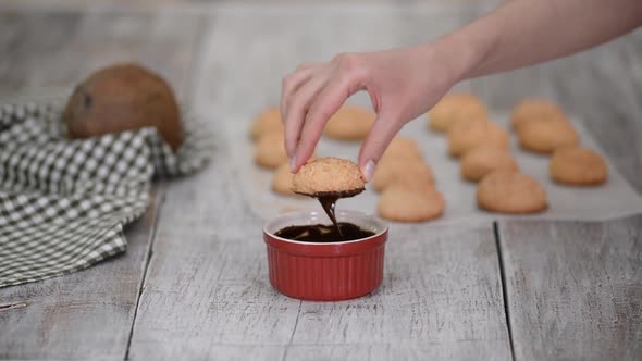 Dipping a Coconut Macaroon Cookie in Melted Dark Chocolate