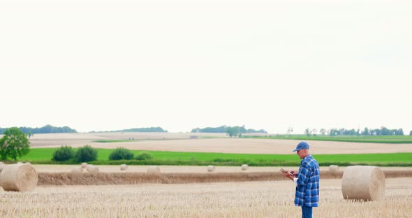 Farmer Using Digital Tablet While Examining Field alt