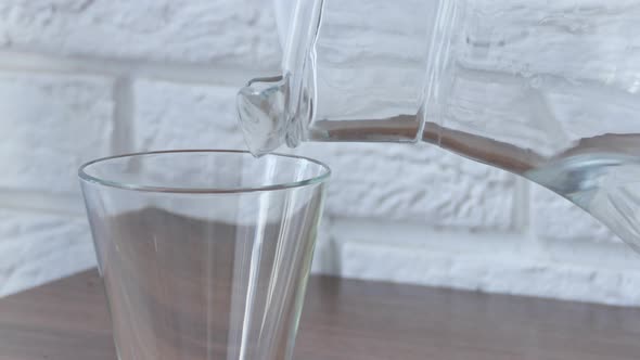 Pure Water is Poured Into a Glass Cup From a Transparent Decanter Closeup
