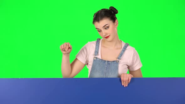 Girl Looking Out From Behind Blue Blank Placard Looks at Him and Shakes His Head Disapprovingly or alt