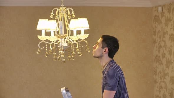 A Man Unscrews a Burnt Out Light Bulb alt