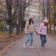 Mom and Daughter are Walking Along an Autumn Alley with a Dog - VideoHive Item for Sale