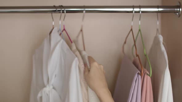 Woman Sorting Through Clothes Hangers in Closet Choosing Outfit Hands Closeup