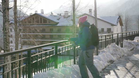 Young Sporty Tourist Woman is Walking in Small Mountain Town at Winter alt