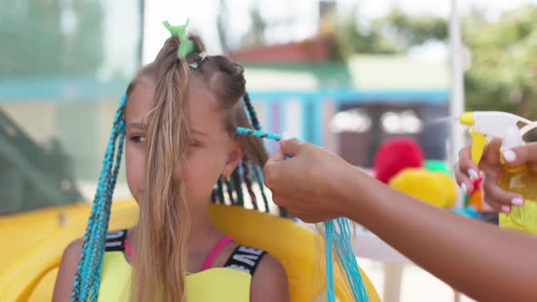 A Girl in a Suit Weaves African Braids in Her Hair on a Sunny Day alt