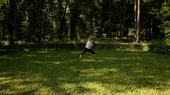 Woman Goes in for Sports in the Early Morning in the Park Among the Trees