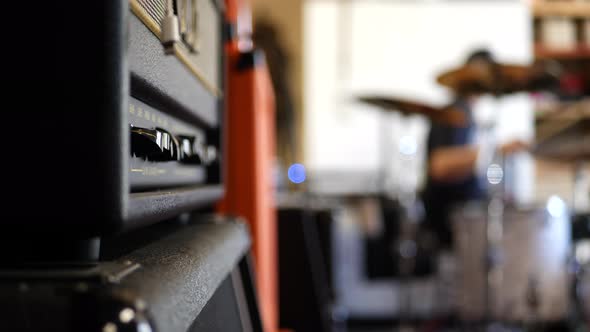 A vintage electric guitar tube amp with a rock and roll garage band drummer in the background SLOW M alt