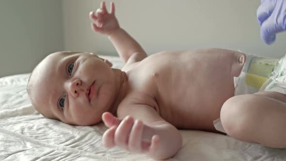 Neonatologist in Latex Gloves Examines a Newborn Baby with a Stethoscope. Close-up. alt