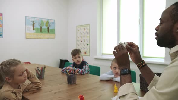 An African American Teacher and a Group of Children are Studying Fruits and Animals in the Classroom alt