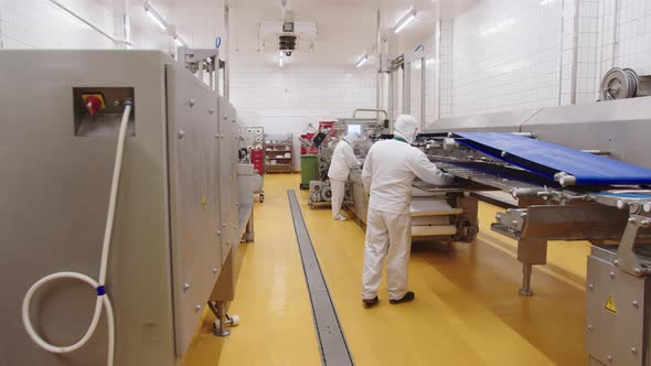 Workers in Uniform Supervise the Operation of Automatic Line for Production of Meat Products for