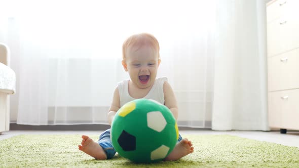 Readhead Baby Girl Playing with a Soccer Ball on the Floor in Sunny Room