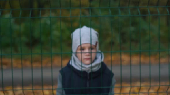 Abandoned Lonely Boy Behind a Fence Autumn Season
