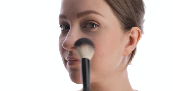 Closeup of Young Caucasian Woman Making Blush on the Face Using Makeup Brush