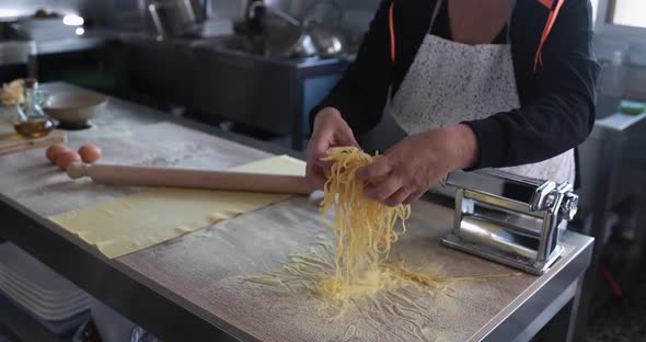 Woman working inside pasta factory while doing fresh italian tagliolini alt