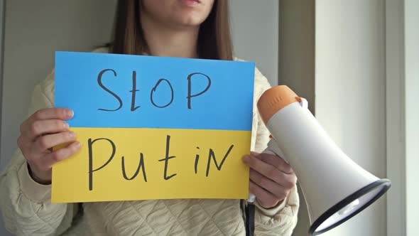 Young Woman with a Poster STOP PUTIN and a Megaphone in Her Hands Calls for an End to the War in