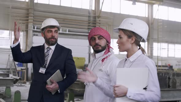 Mixed-ethnic business people going through factory