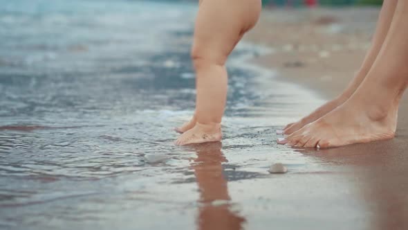 Mother and Baby Foot Walking on Sand Beach. Newborn Kid Feet at Beach alt