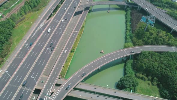 Aerial Tilt View of a Highway Overpass Multilevel Junction with Fast Moving Cars Surrounded By Green alt