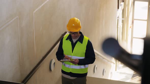 Builder in Helmet with Clipboard on Stairs