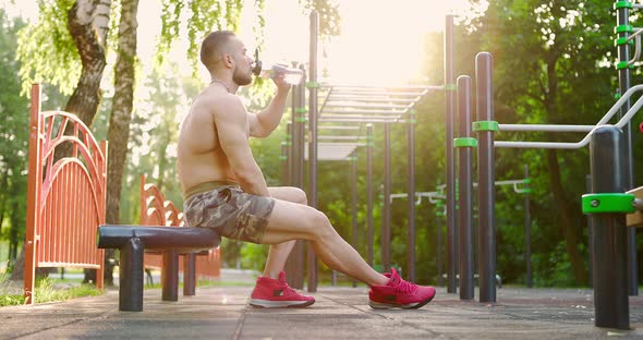 Sporty Man Drinking Water After Intense Training Outdoor alt