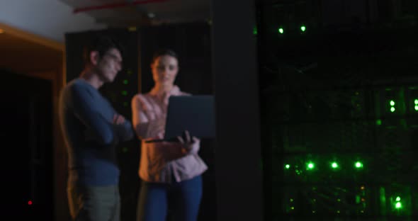 Diverse female and male it technicians using laptop checking computer server alt