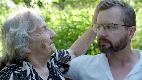 an Old Woman Strokes on the Head of Her Adult Relative Grandson with an Intelligent Look and Similar alt
