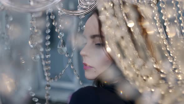 Alluring Woman in Black Dress Posing with Luxury Shiny Chandelier Dramatic and Romantic Look alt