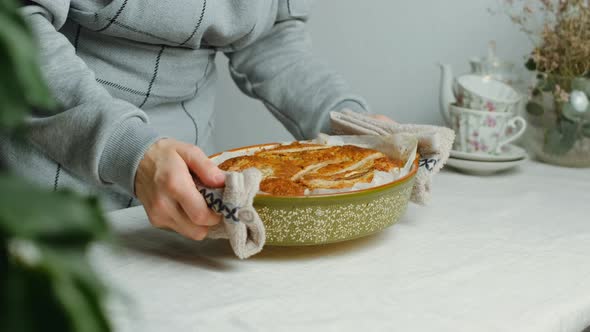Housewife Puts Baking Dish for Banana Pie on Table  alt